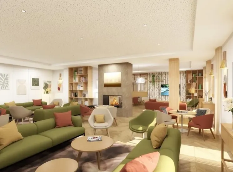 Main lounge of the OBEO senior residence in Éragny-sur-Oise: green sofas and terracotta armchairs around the fireplace, with a library corner and TV area bathed in light
