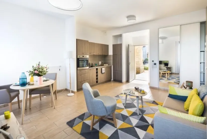 Furnished studio at the OBEO Éragny-sur-Oise residence: dining corner, open fitted kitchen, blue armchairs and a graphic rug