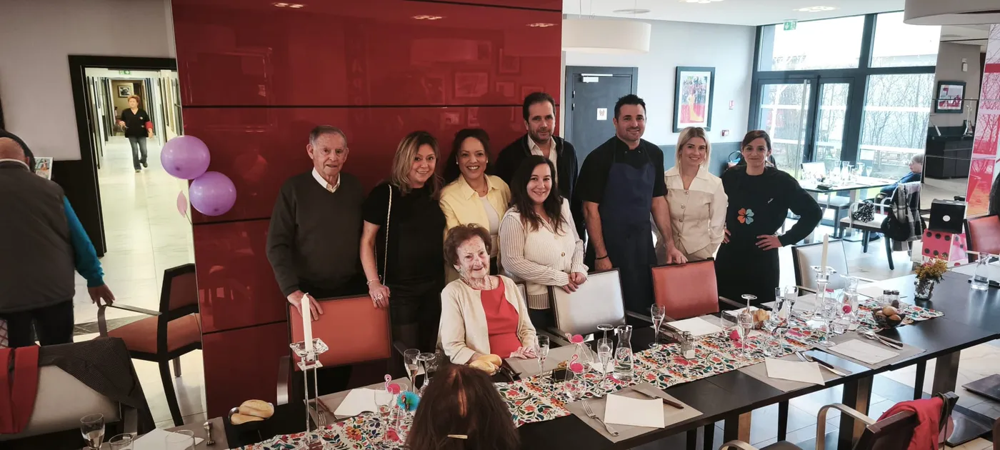 Residents and staff gathered behind the long decorated table set for the birthday lunch