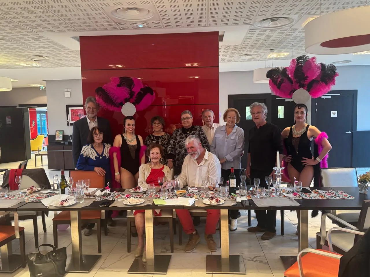 Residents, relatives and staff posing together around the party table with the two cabaret dancers