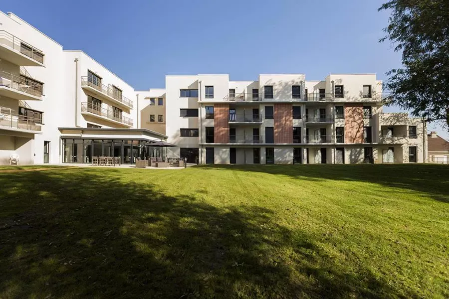 Façade et jardin de la résidence seniors OBEO Nevers, avec terrasse et pelouse ensoleillée