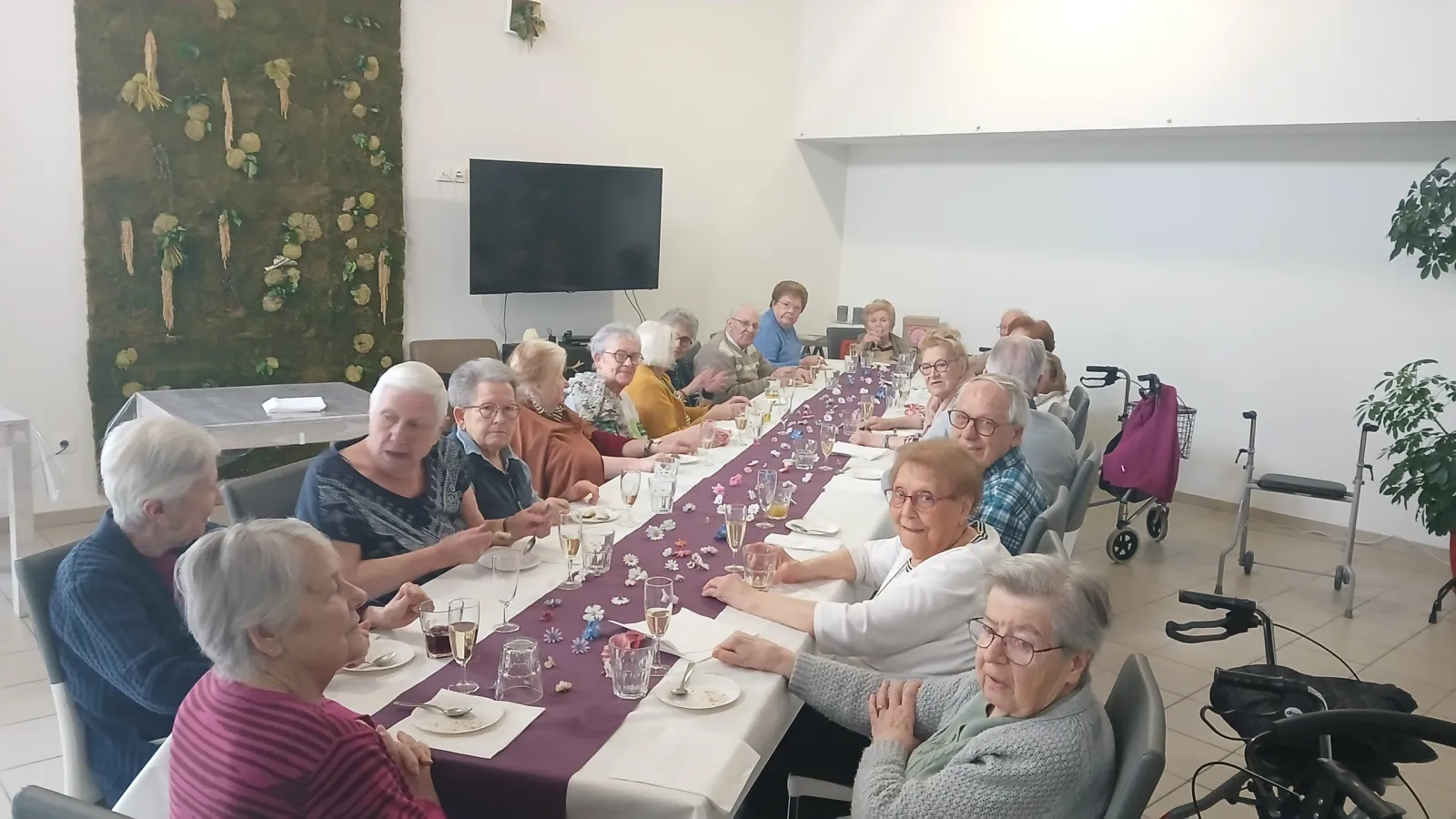 Residents seated along a long table dressed with a purple runner in the dining room