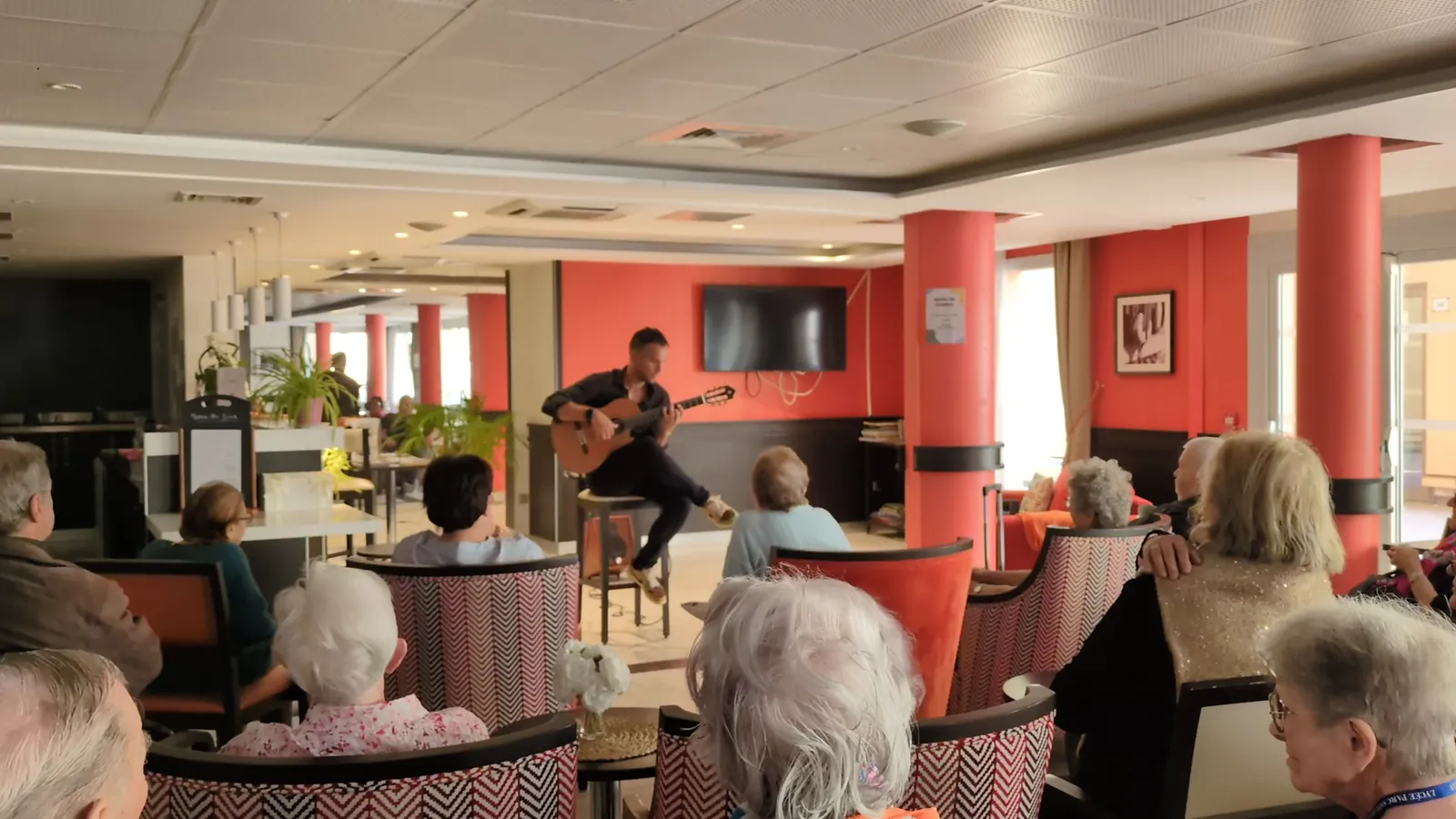 Residents settled in armchairs in the lounge, listening to a guitarist play