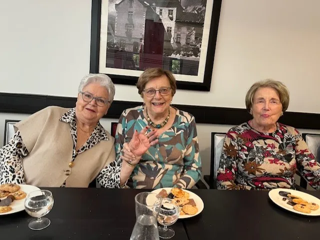 Three residents smiling at the table, plates of chocolate treats in front of them