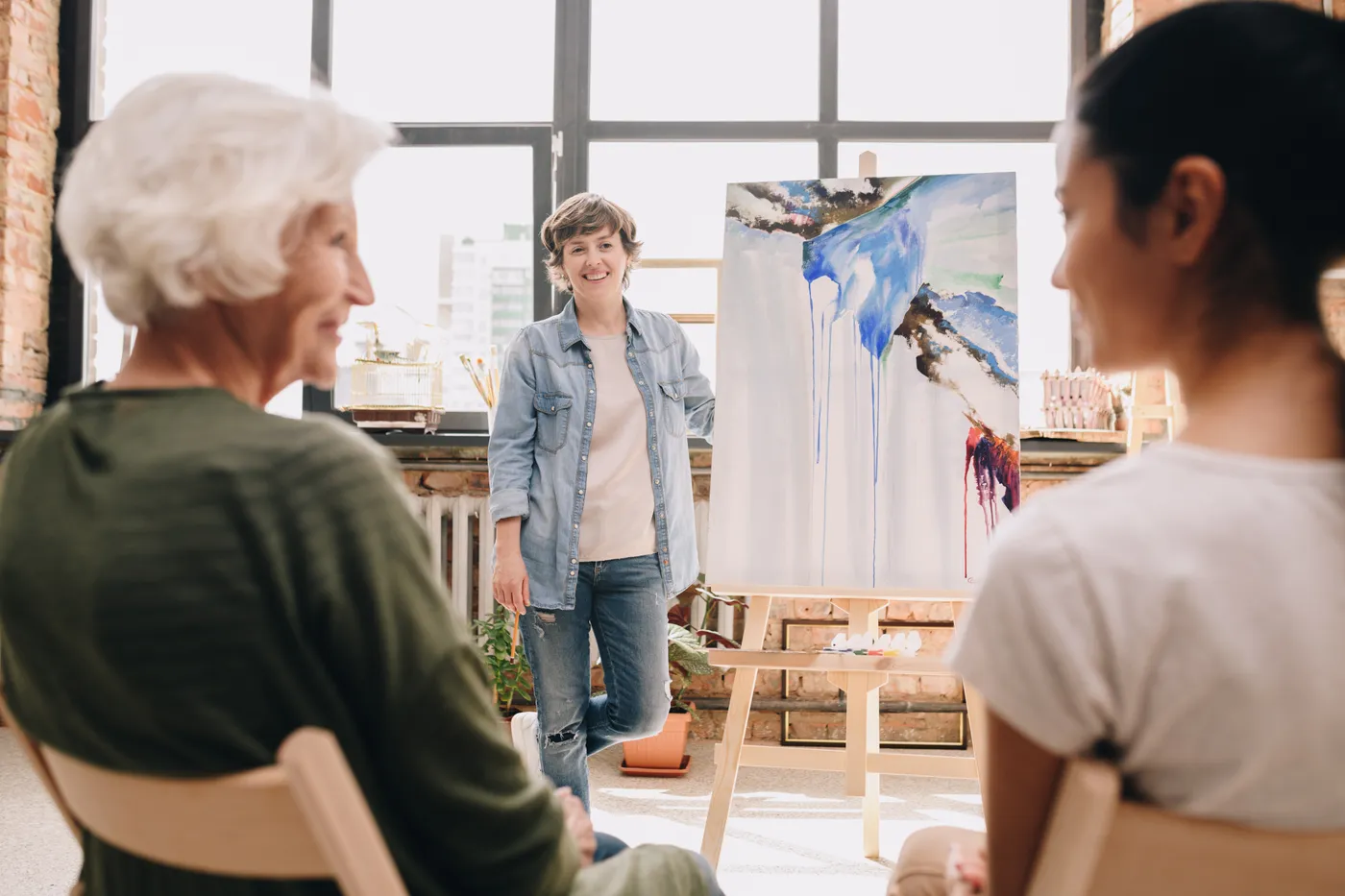 Un cours de dessin en cours, les participantes devant leurs chevalets écoutent l'intervenant