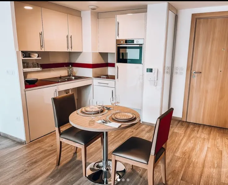 La kitchenette équipée d'un appartement meublé : four, plaques et petite table ronde
