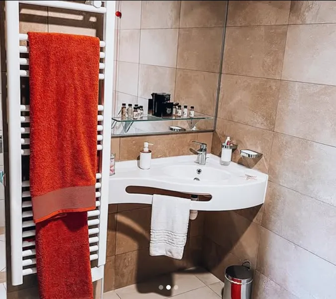 Une salle de bains adaptée : lavabo avec barre d'appui, sèche-serviettes et serviette rouge