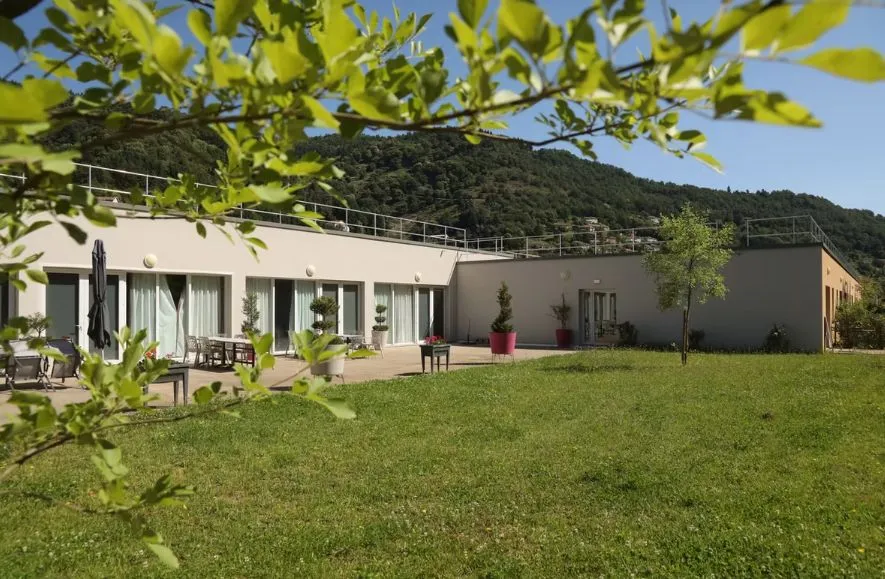 La résidence de plain-pied et sa terrasse vues depuis la pelouse, les collines en arrière-plan
