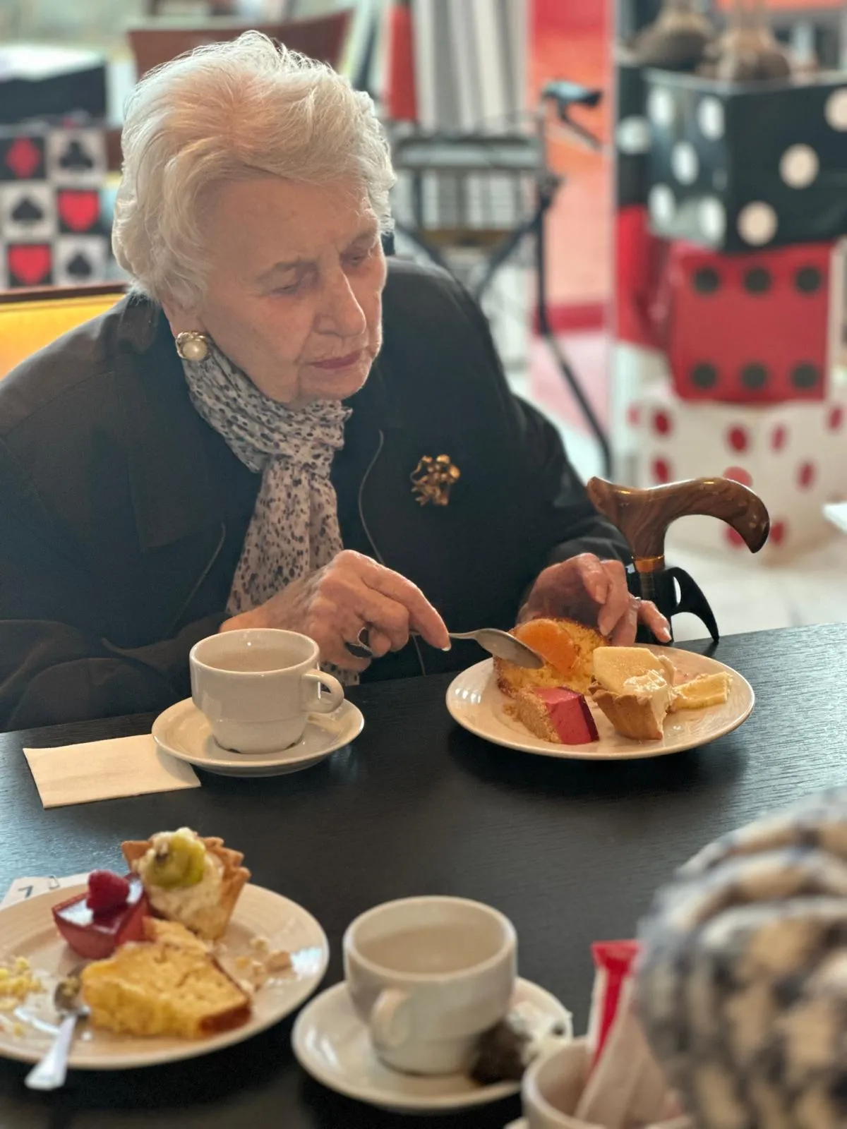 Une résidente découpe sa part de gâteau, tasse de café et bulletin de vote sur la table