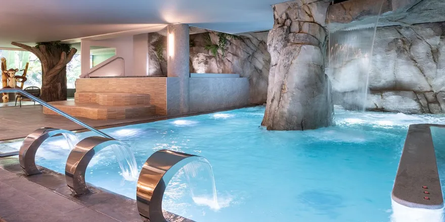 Un bassin thermal intérieur agrémenté de rochers et de jets d'eau