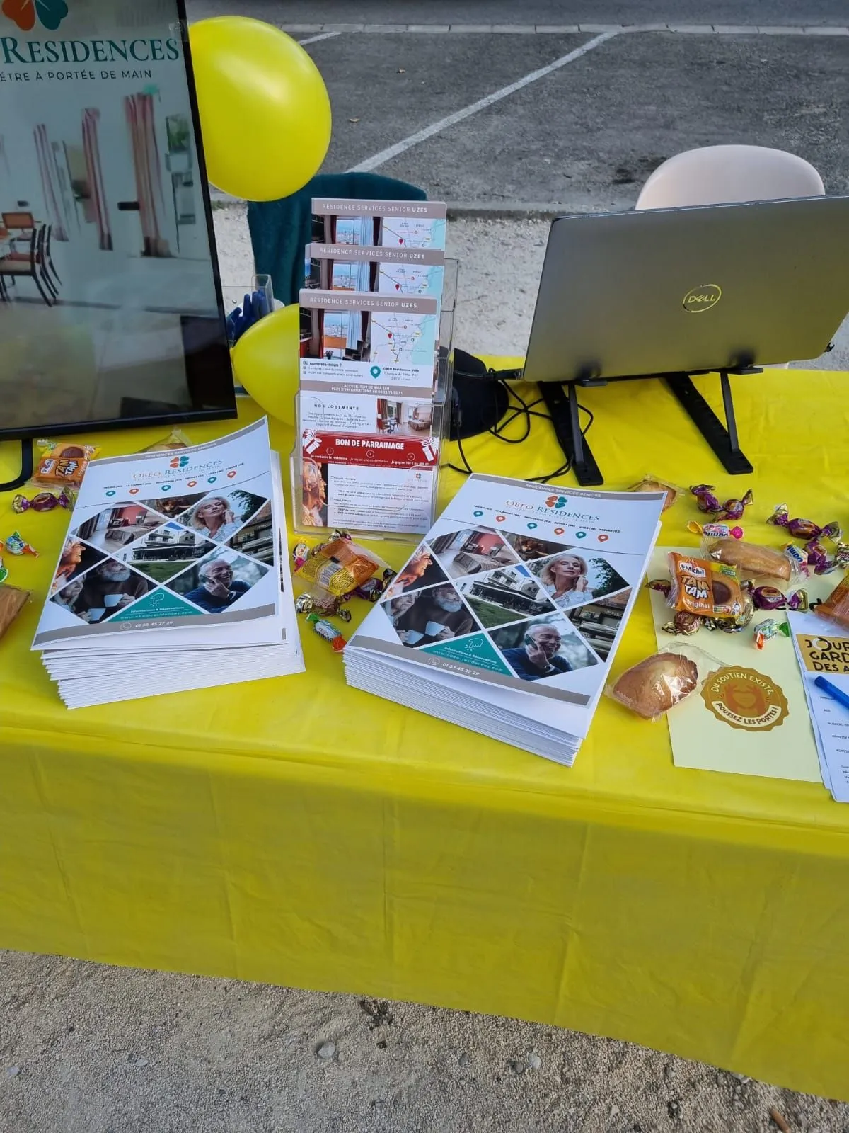 Gros plan sur la table du stand couverte de brochures, de bonbons et de ballons jaunes