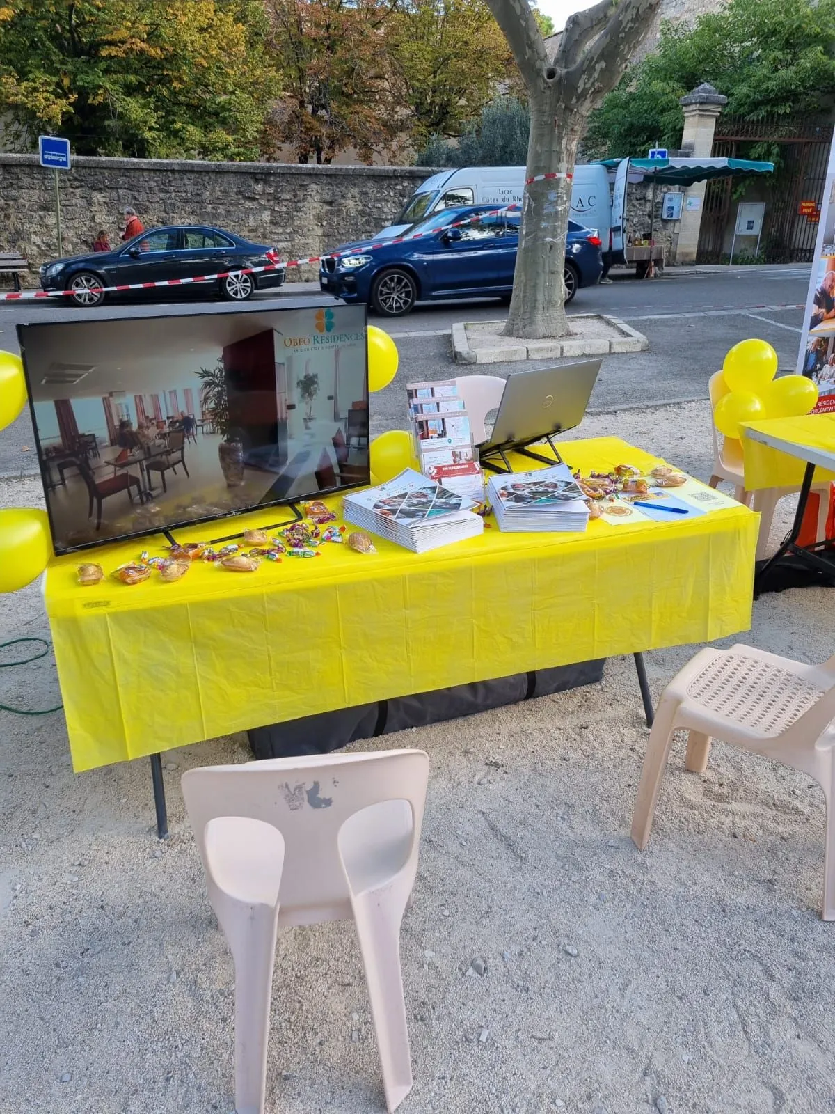 Le stand de la fête des aidants vu depuis la place, écran et brochures sur la table jaune