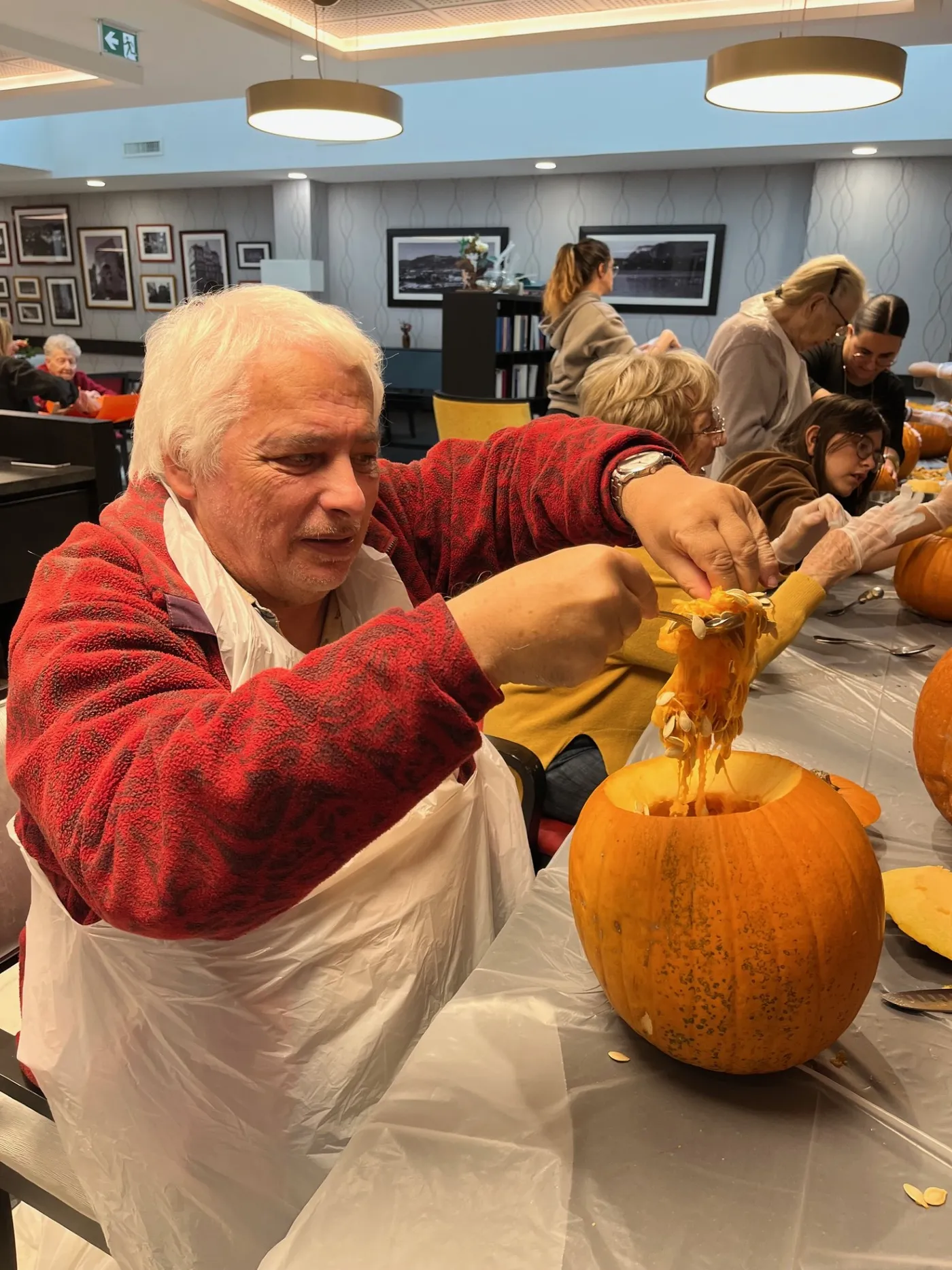A resident scooping the flesh out of a pumpkin, hands deep inside