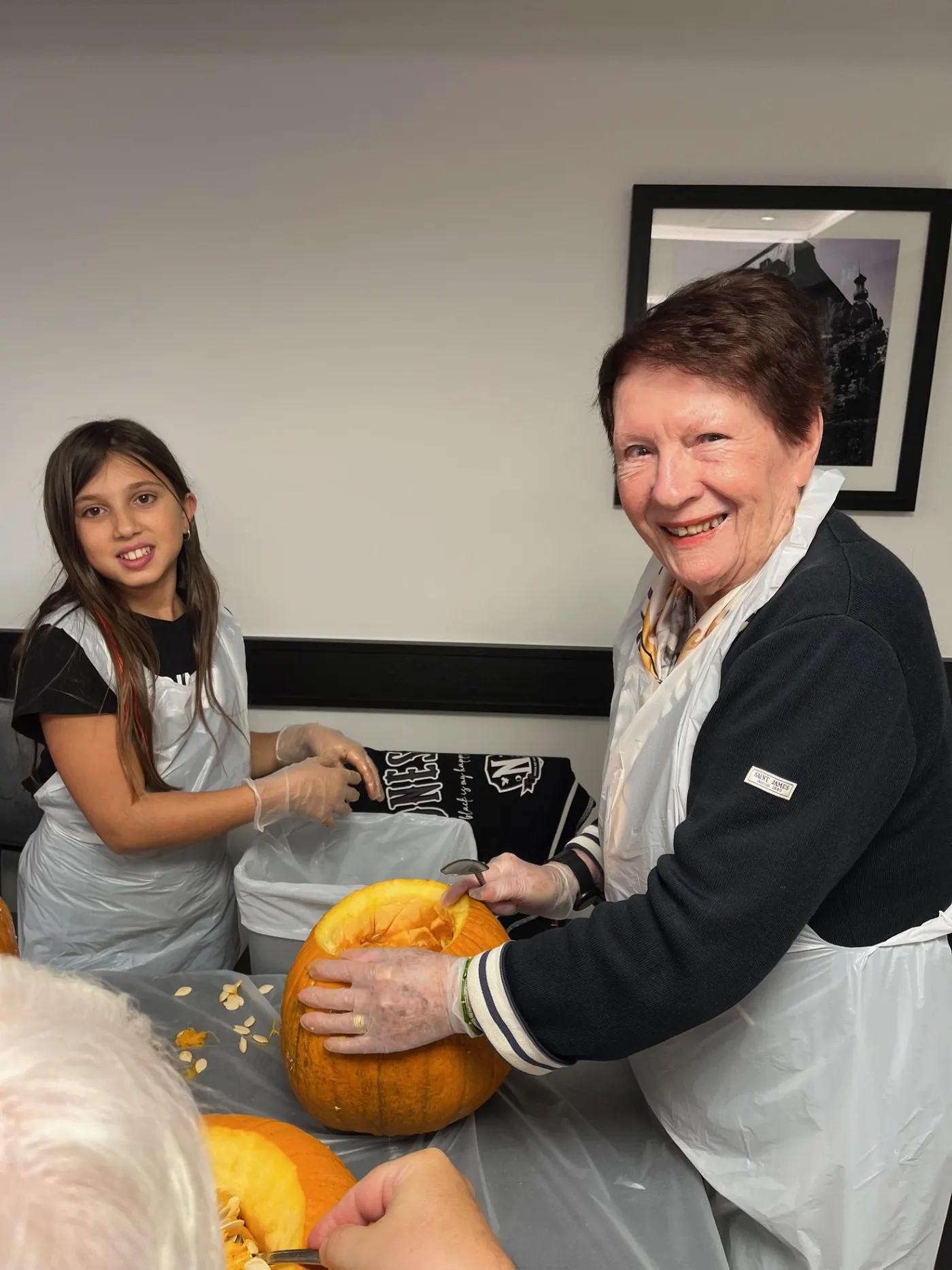 A girl and a member of staff carving a face into a pumpkin together