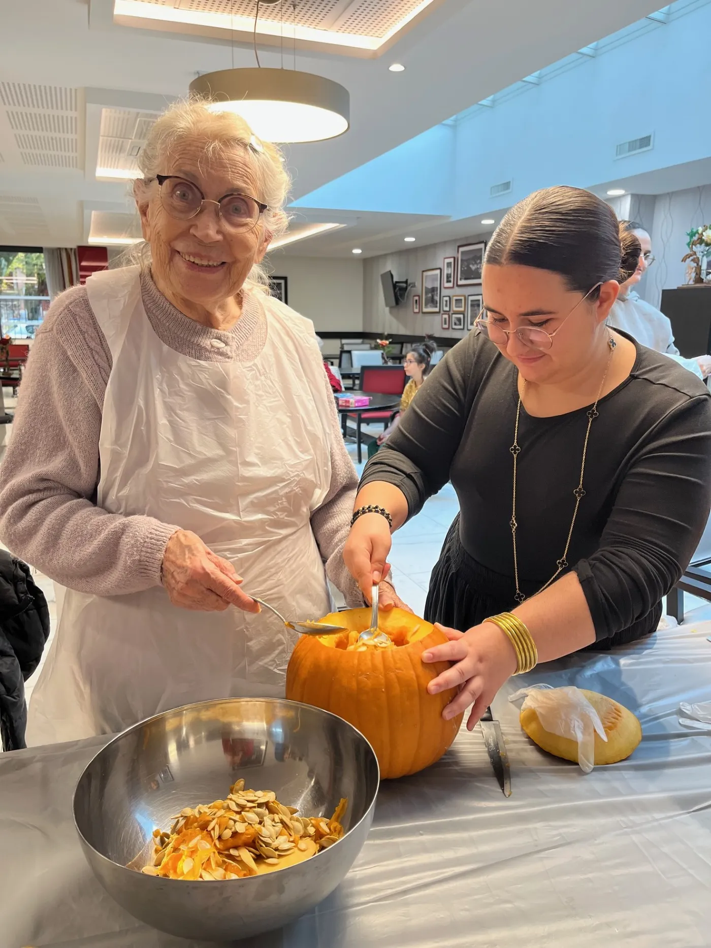 A resident and a facilitator emptying pumpkin flesh into a metal bowl