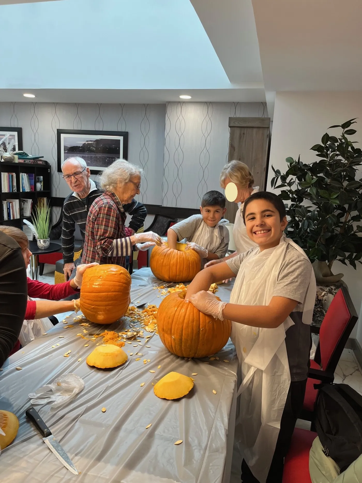 Children in aprons helping residents scoop out their pumpkins