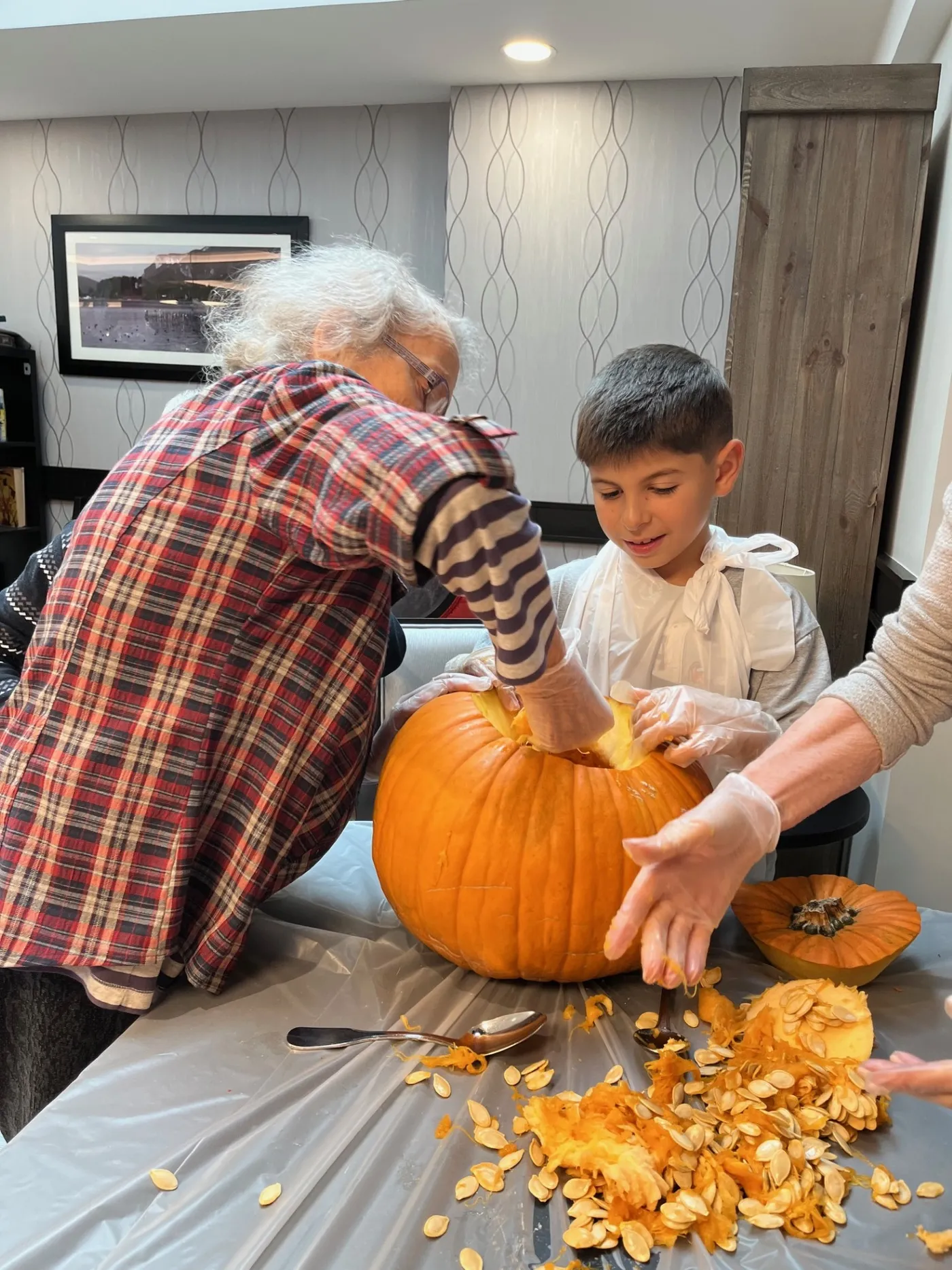 A resident and a young boy pulling the seeds out of a pumpkin together