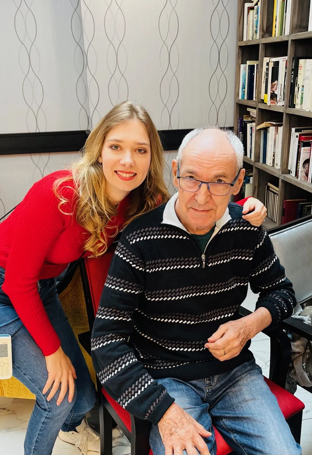 A young volunteer leaning in beside a resident for a photo in the library corner