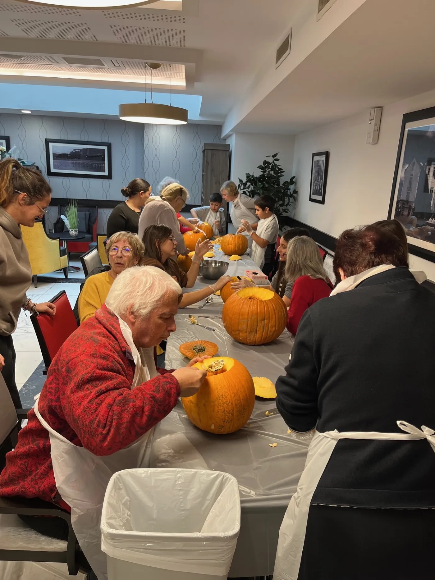 Residents and children around the tables hollowing out pumpkins together
