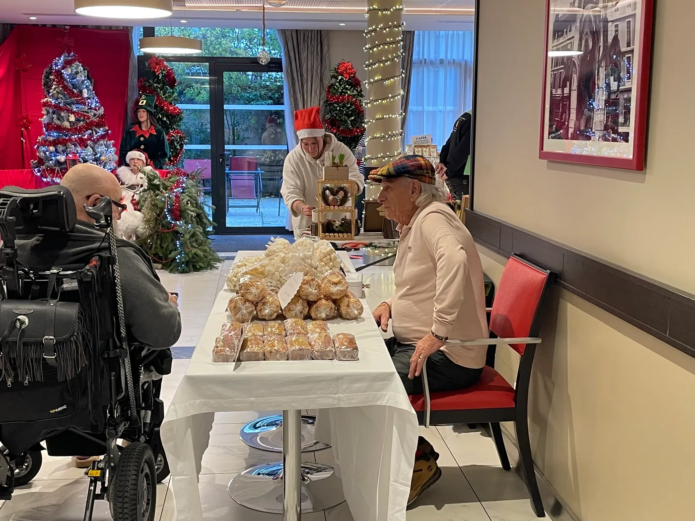 A member of staff offering a tray of pastries to residents in the corridor
