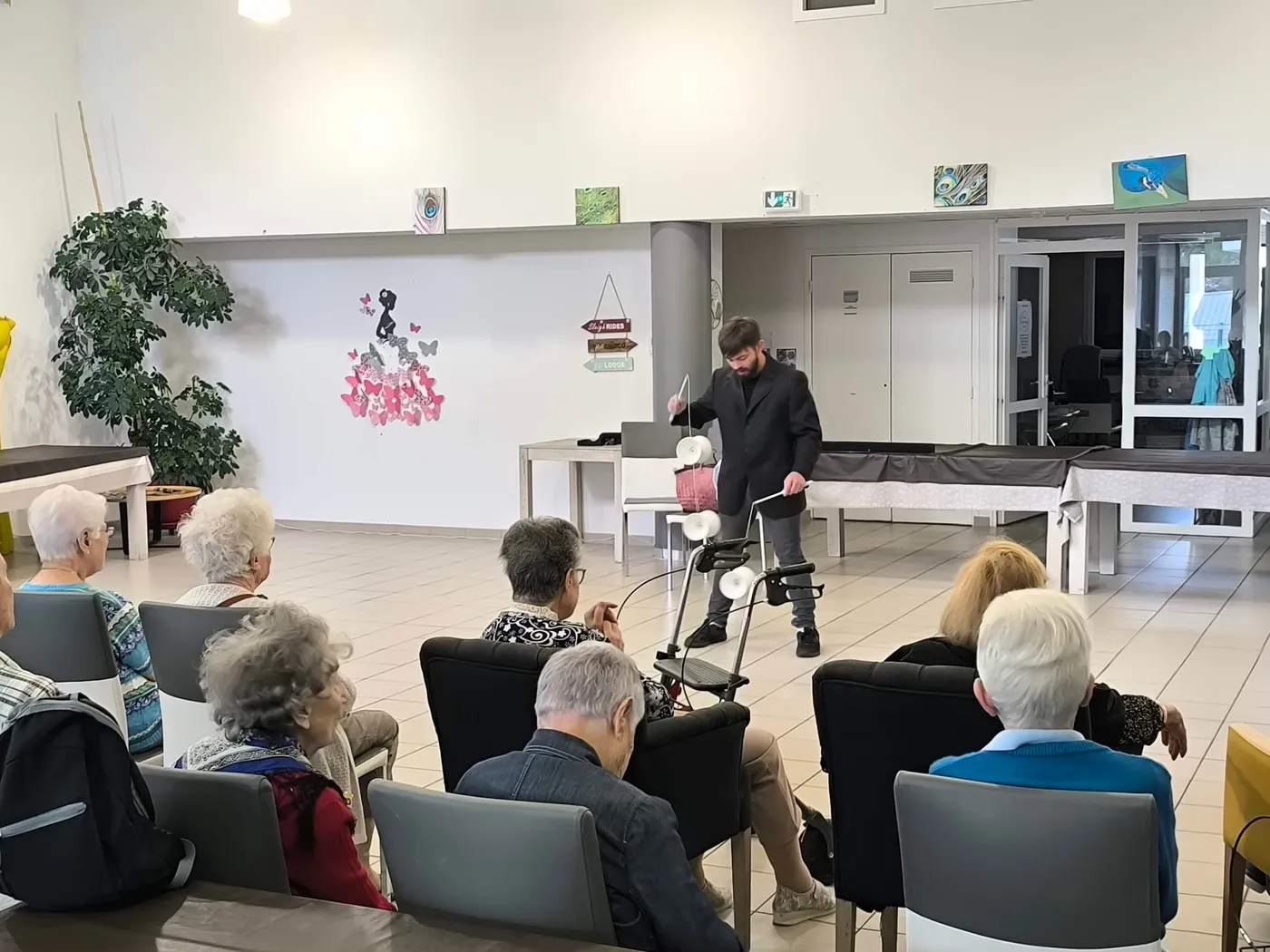 Des résidents assis devant une petite scène pendant l'après-midi brocante