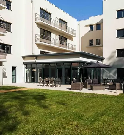 La terrasse vitrée de la résidence et sa pelouse vues depuis le jardin