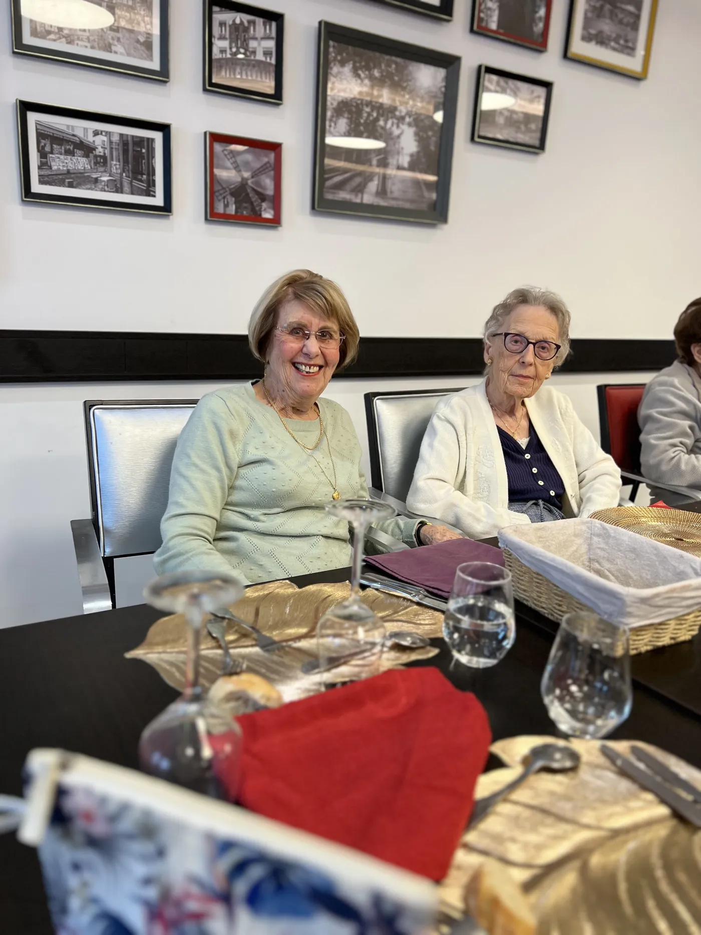 Two residents sitting side by side at the table, framed photographs on the wall behind