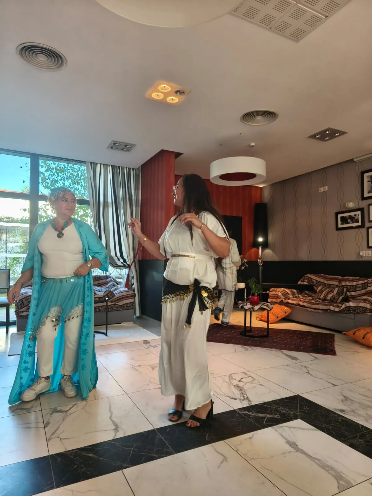 Two performers in flowing turquoise and white costumes dancing in the lounge