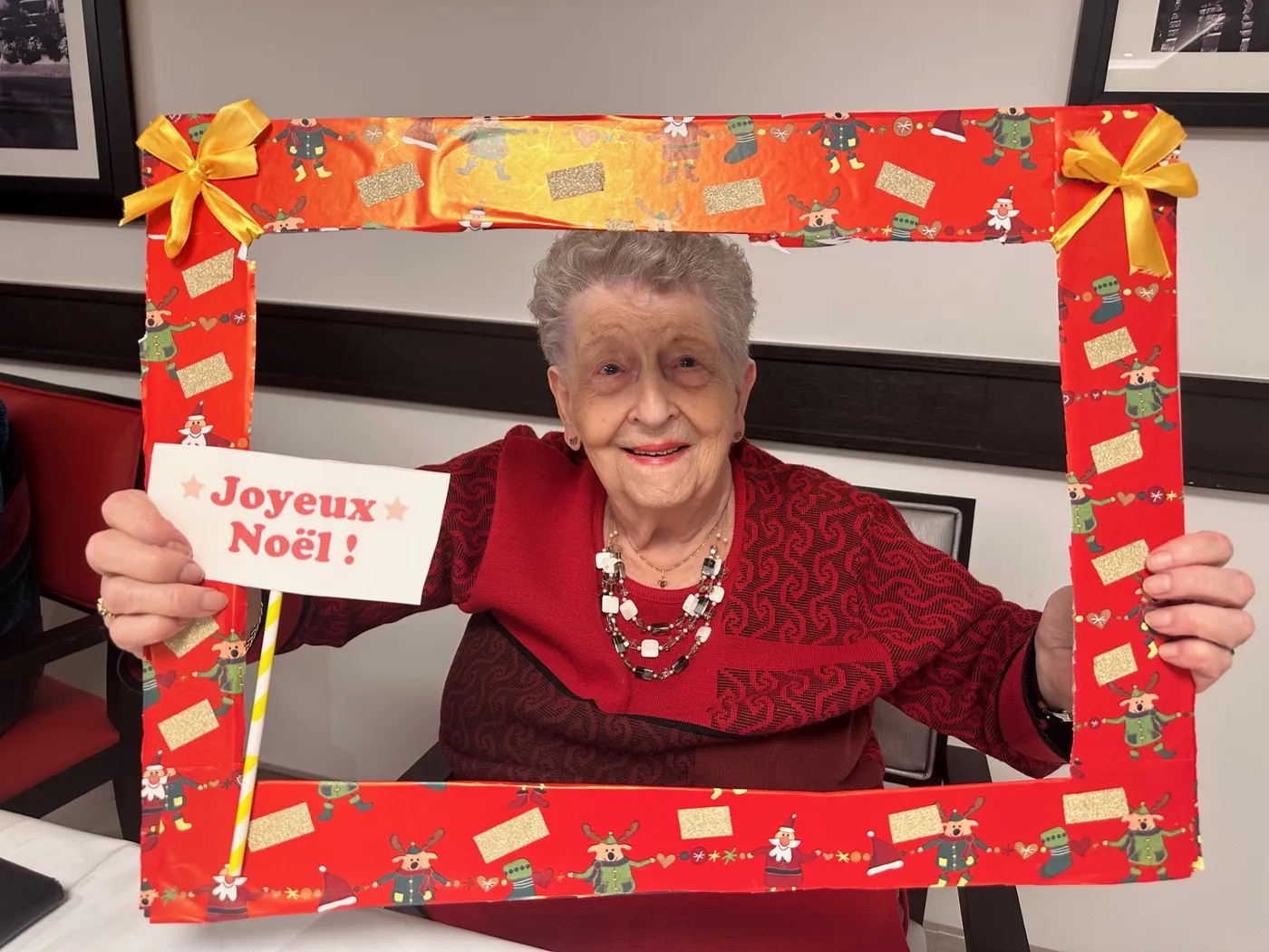 A resident holding up a handmade photo frame with a Merry Christmas card in French