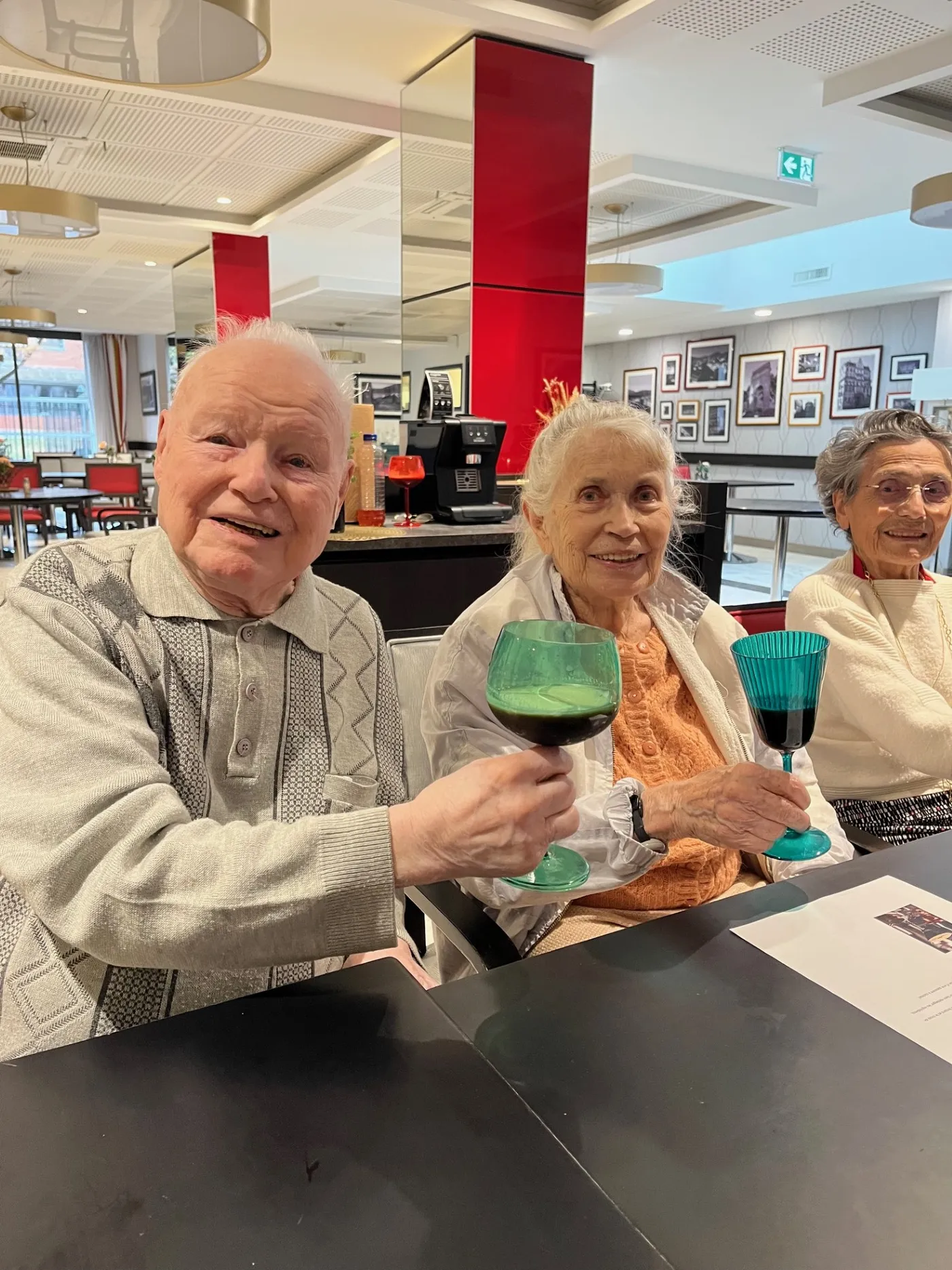 Three residents raising green cocktails at the table