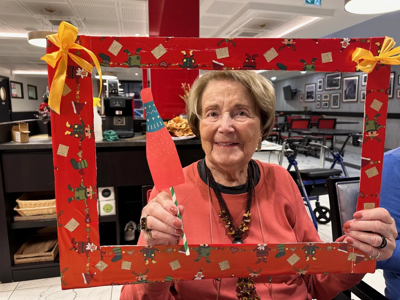 A resident holding up a red handmade photo frame in the lounge