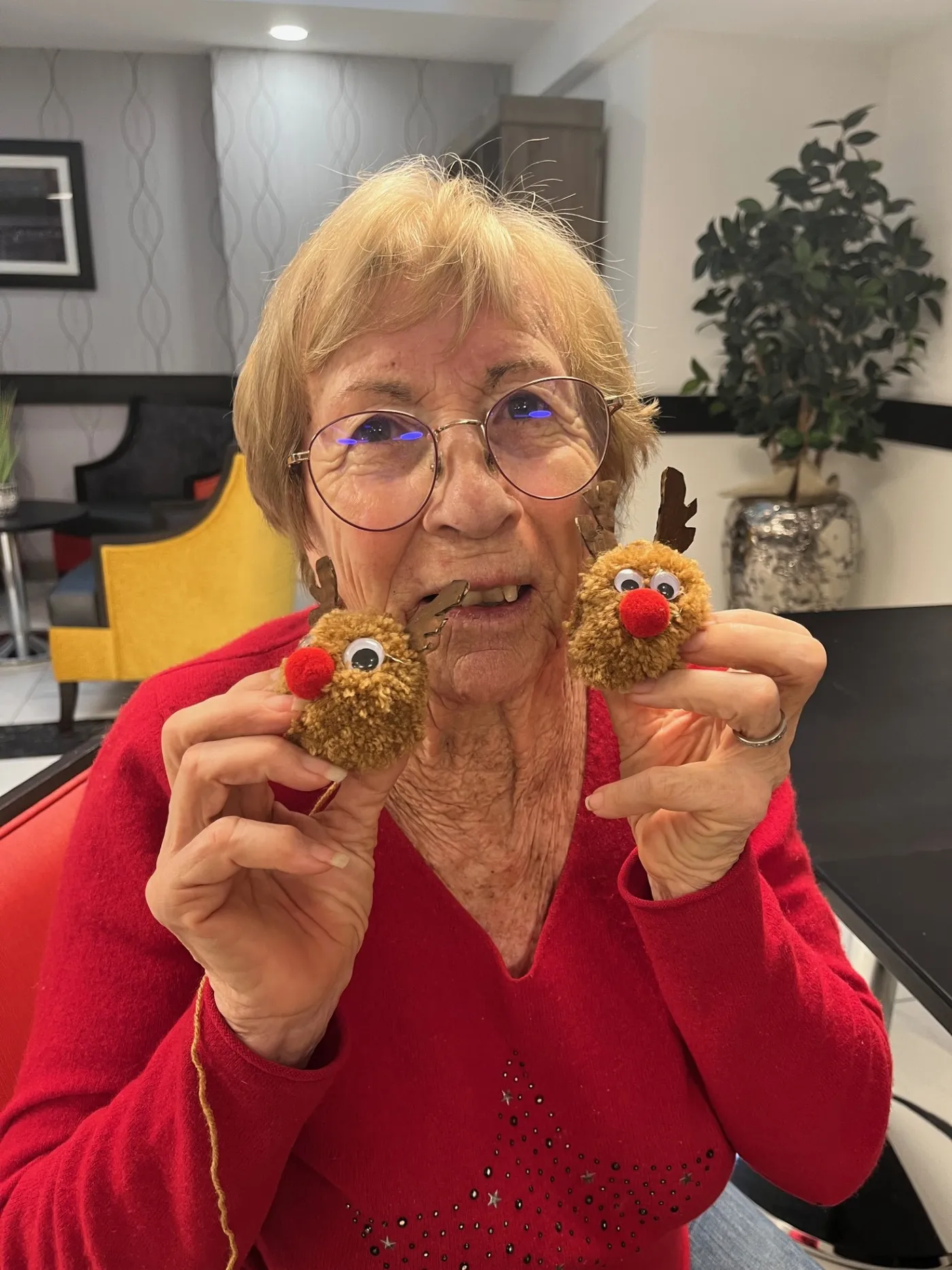 A resident holding up two handmade reindeer decorations