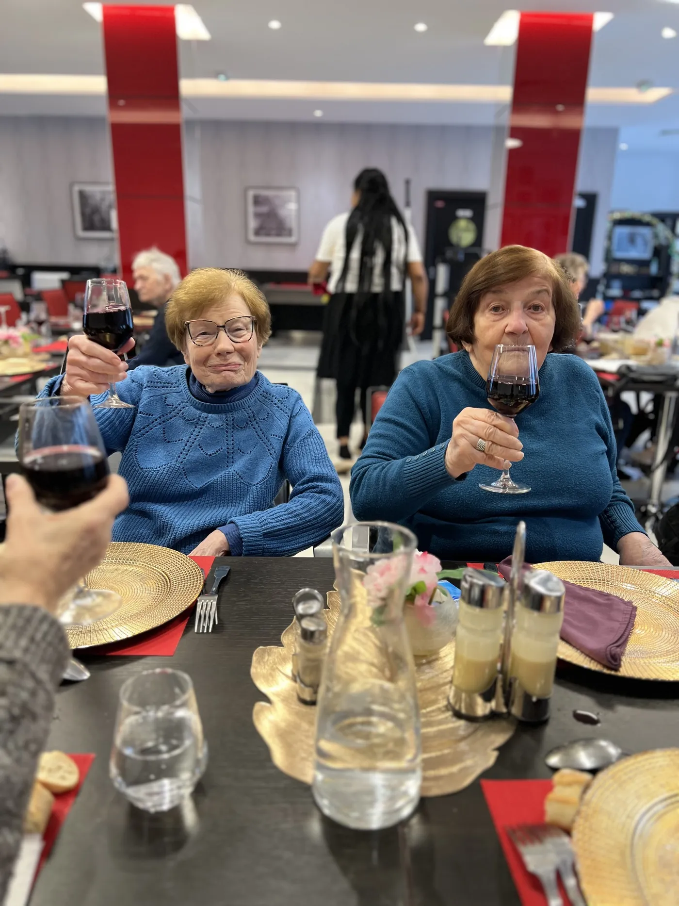 Deux résidentes lèvent leur verre de vin dans la salle à manger animée