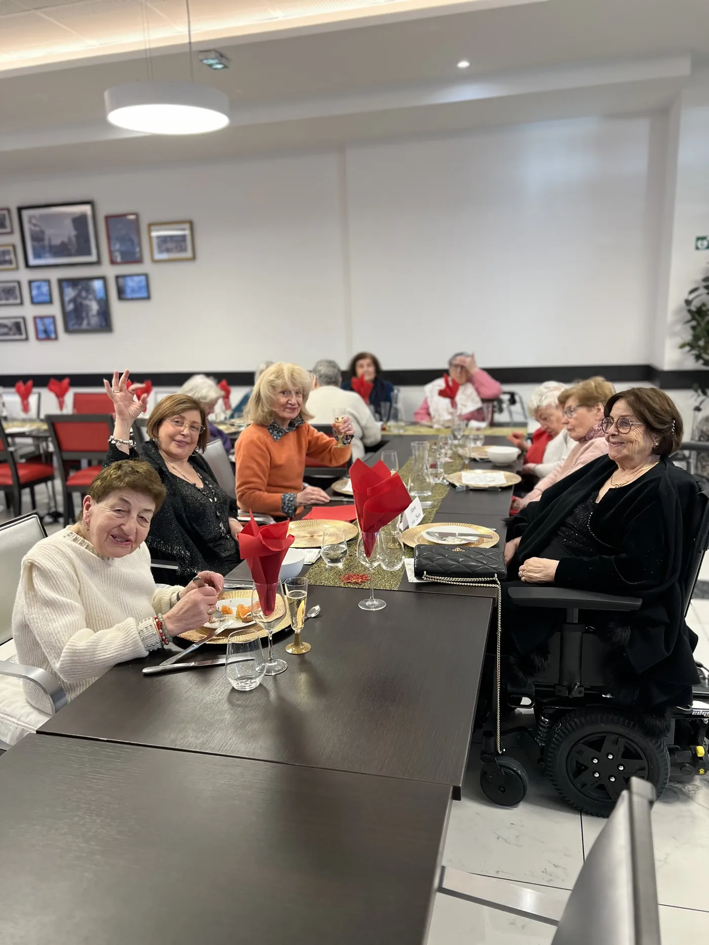 Des résidentes attablées pendant le repas de Noël, l'une d'elles faisant un signe de la main