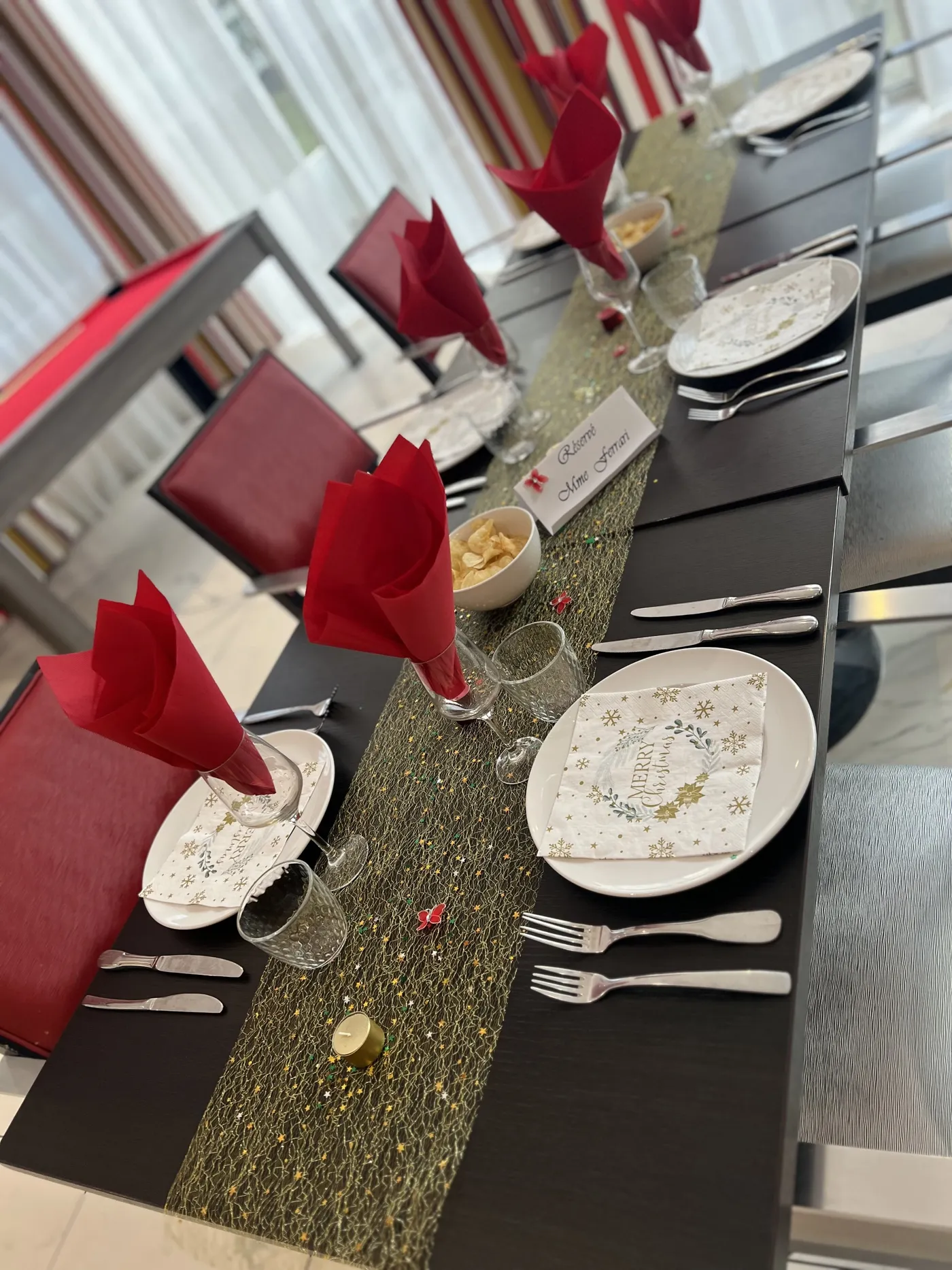 Une table habillée de serviettes rouges, d'un chemin doré et d'assiettes décorées