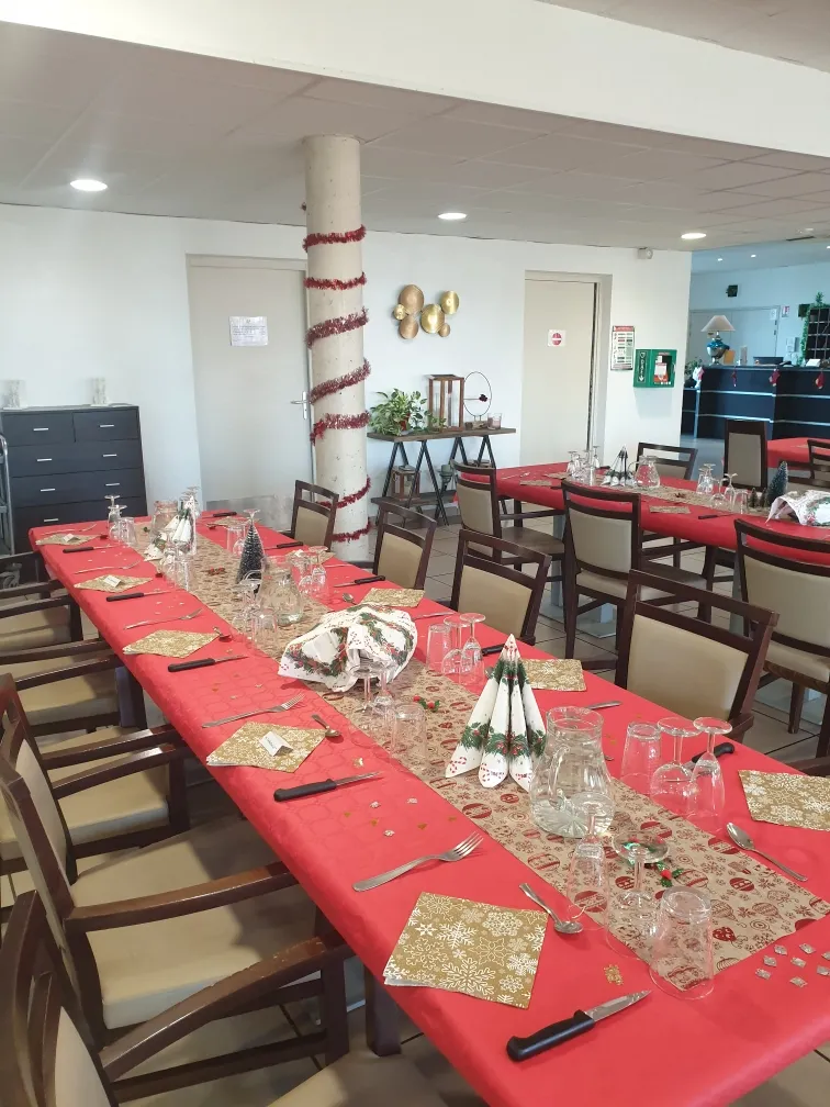 Les tables de la salle à manger nappées de rouge et garnies de sets dorés pour Noël