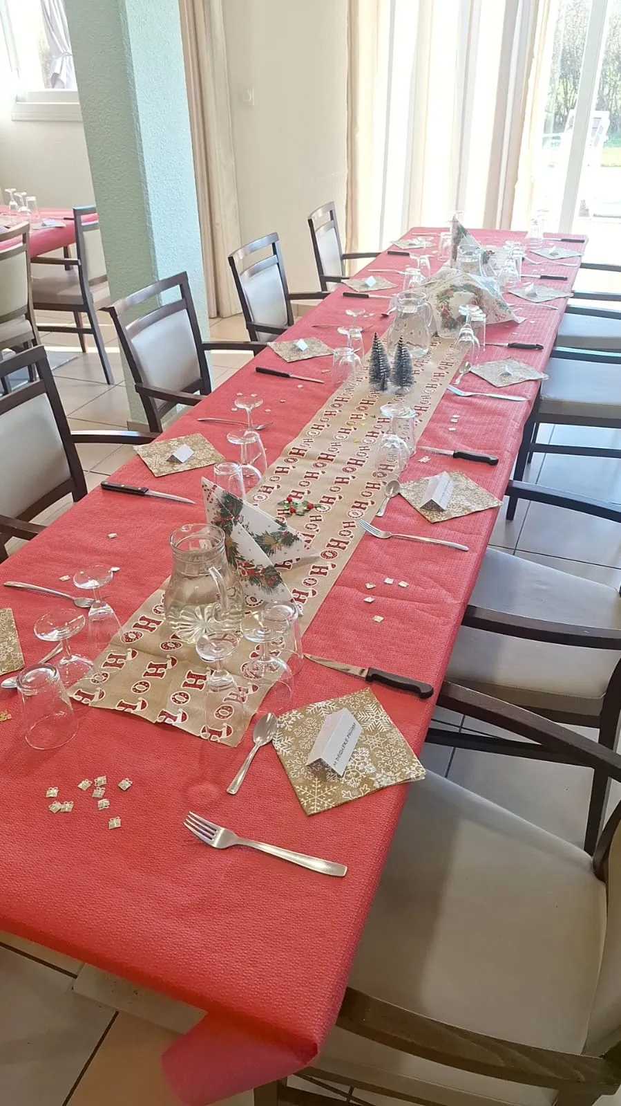 La grande table dressée de sa nappe rouge, de ses verres et de ses sets dorés