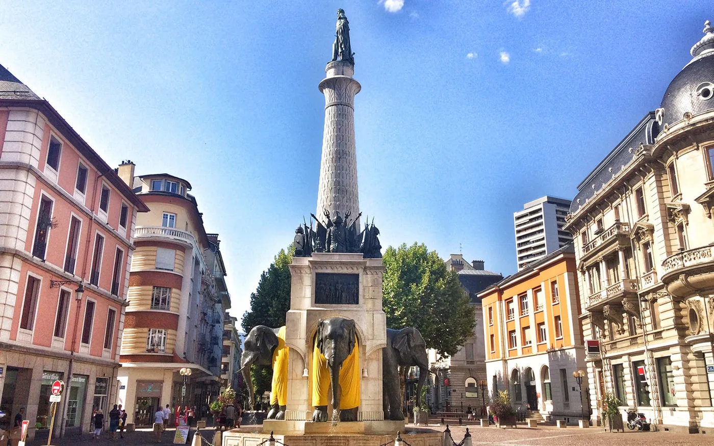 La fontaine des Éléphants et les vieux immeubles de Chambéry sous un ciel bleu
