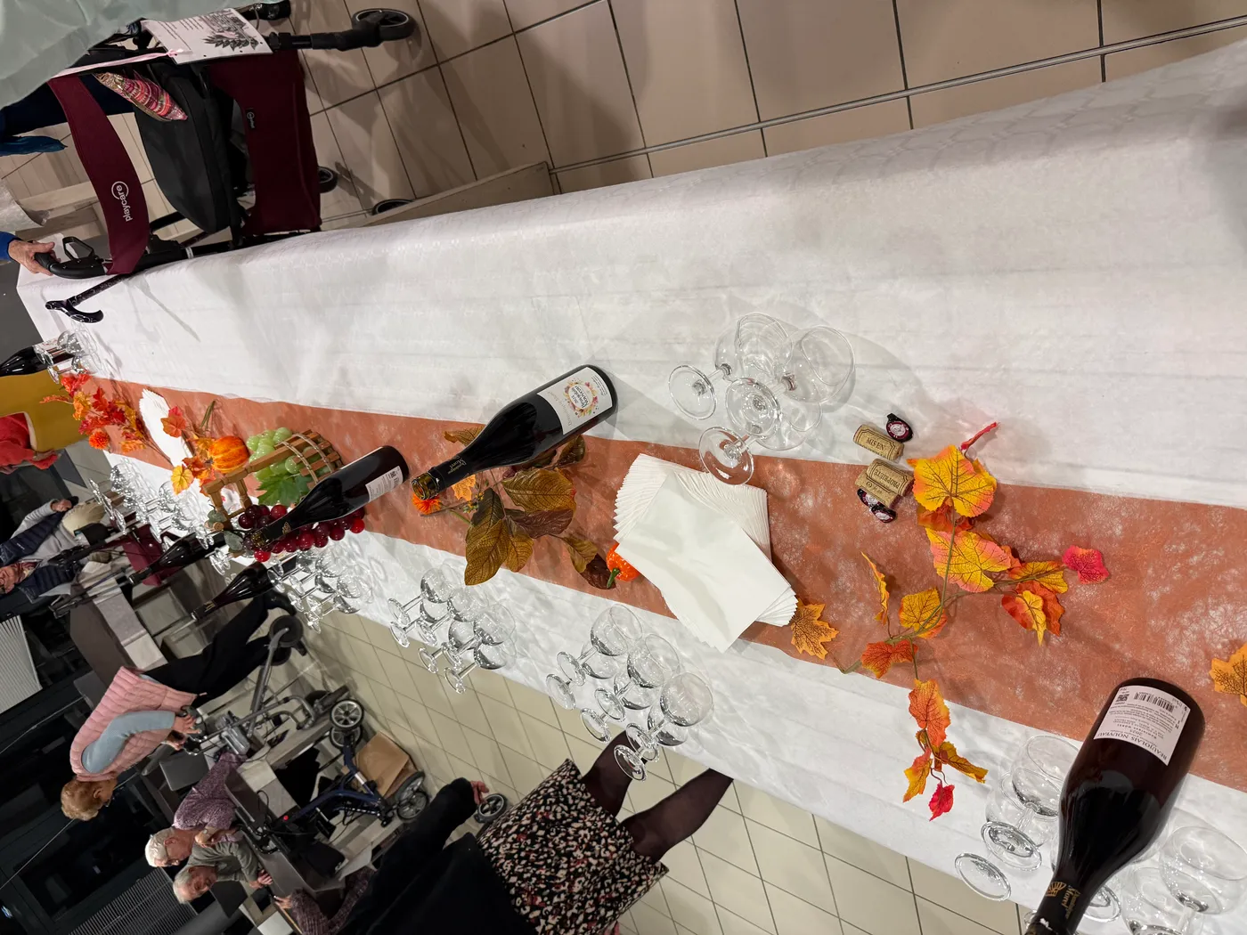 Une longue table décorée de feuilles d'automne et de bouteilles de beaujolais