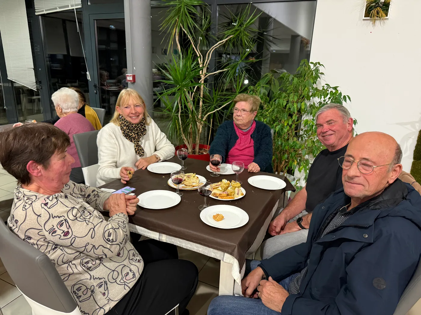 Des convives réunis autour d'une table, leurs assiettes et leurs verres de vin devant eux