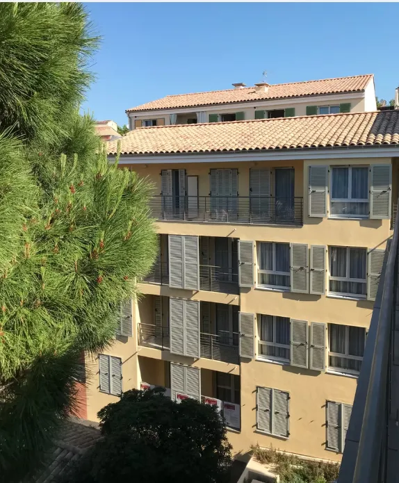 La résidence de Fréjus, sa façade à volets dressée derrière un grand pin