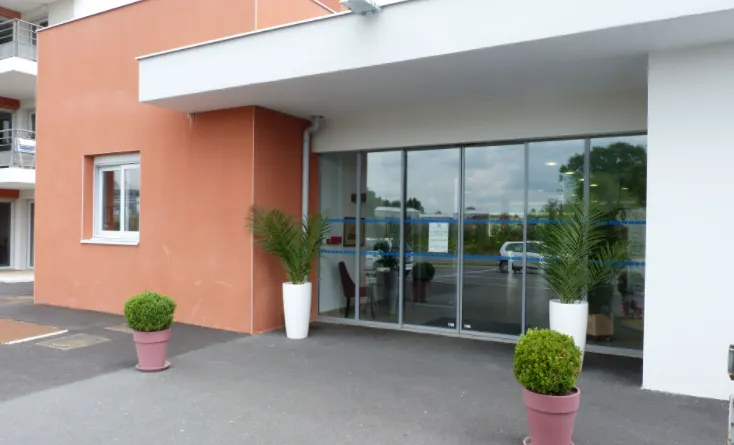 L'entrée de la résidence d'Yzeure, sa façade rose et blanche et ses portes vitrées