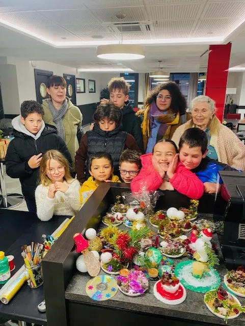 Schoolchildren and staff gathered behind a table of handmade Christmas decorations