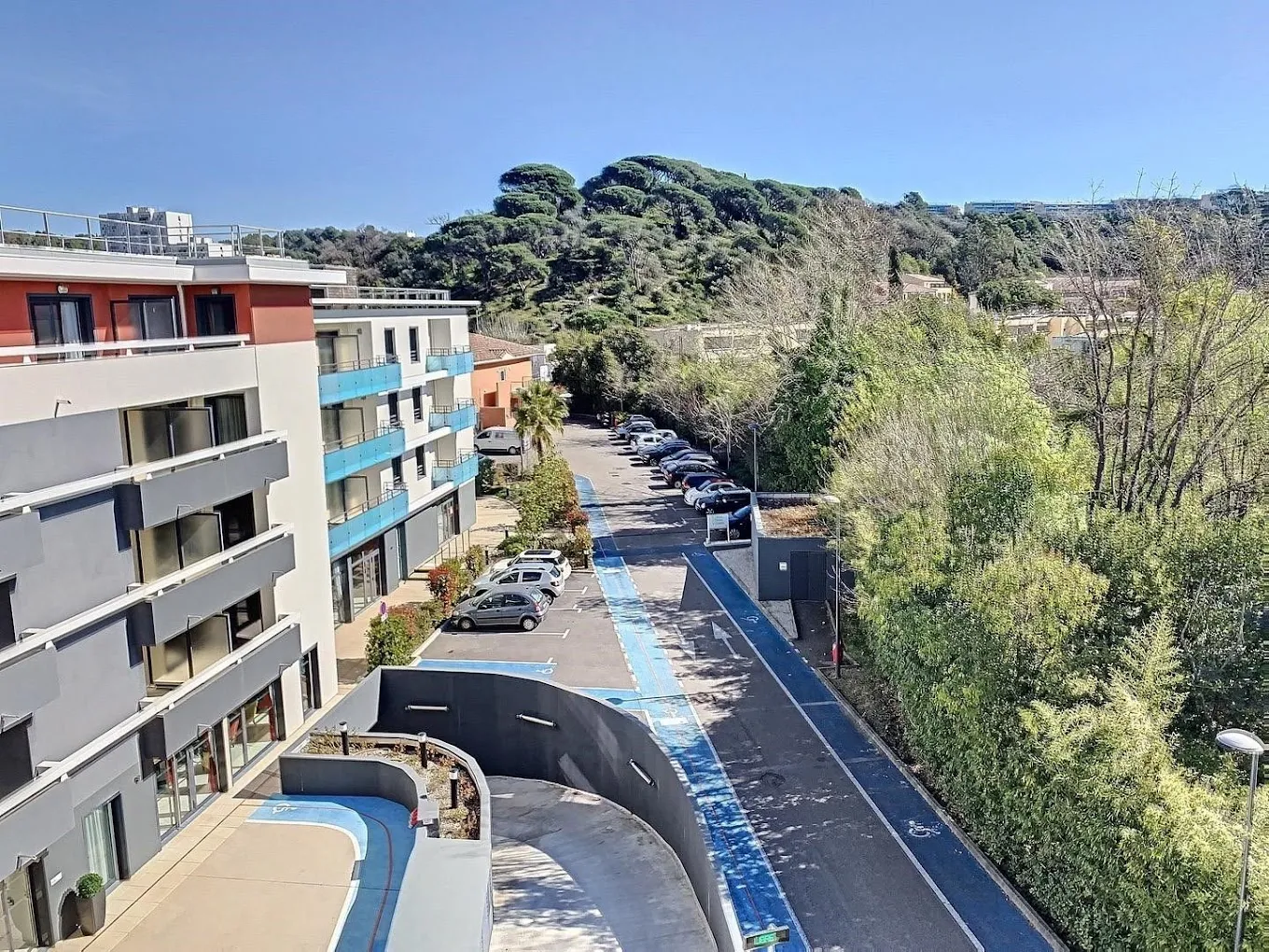 Vue extérieure de la résidence seniors OBEO Le Cannet, bâtiment moderne avec parking et collines verdoyantes