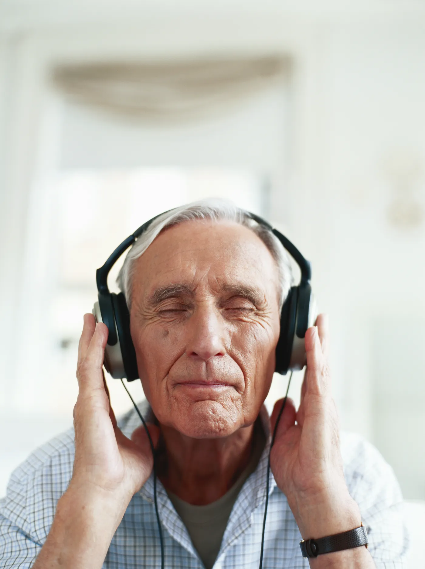 Un homme âgé, les yeux fermés, écoute de la musique dans un grand casque