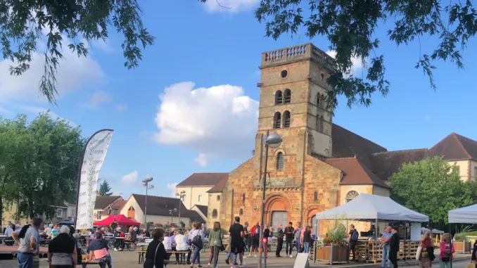 A crowd gathered around stalls and a marquee in front of the church in Yzeure