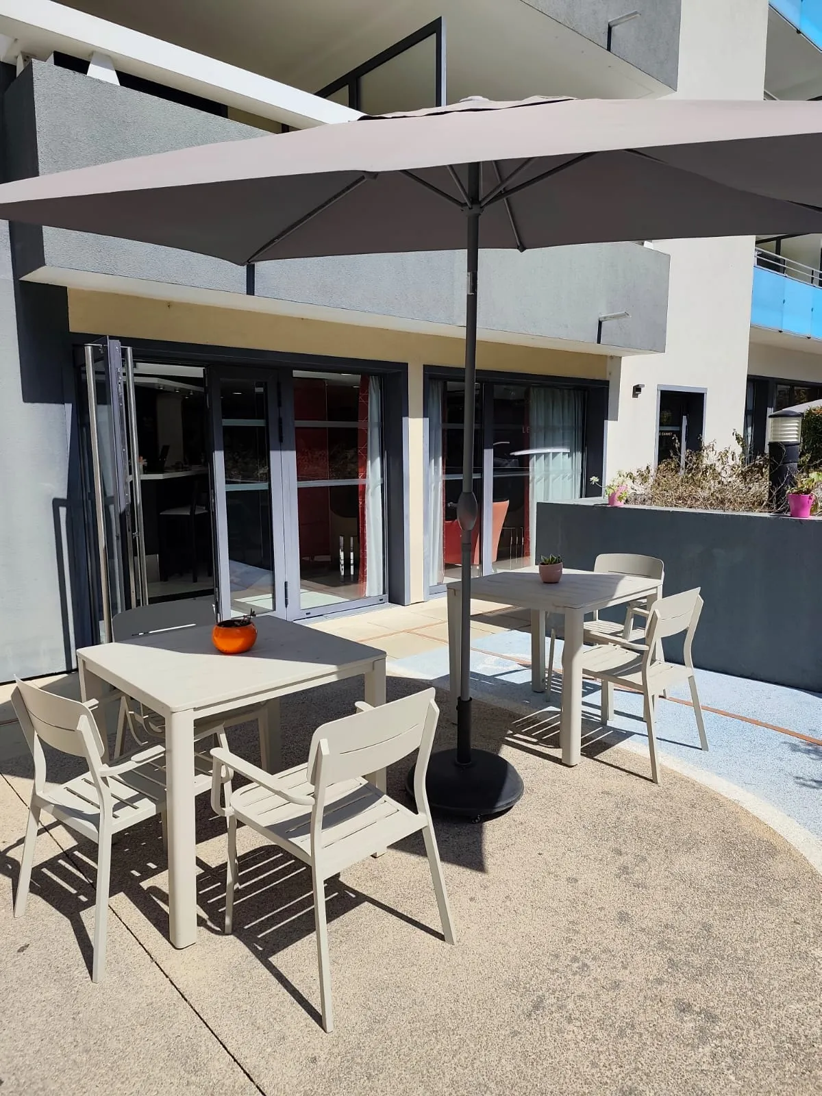 Terrasse ensoleillée de la résidence OBEO Le Cannet avec tables et parasol