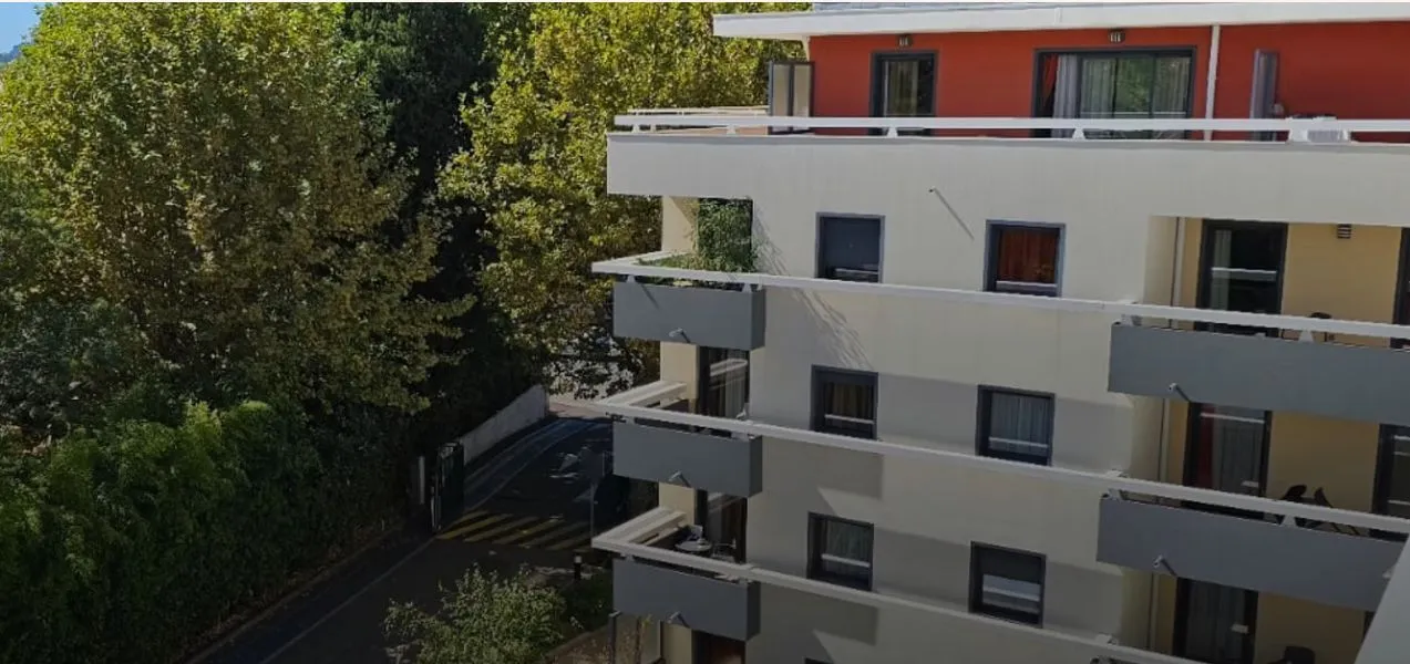The residence's white and red facade seen through the trees