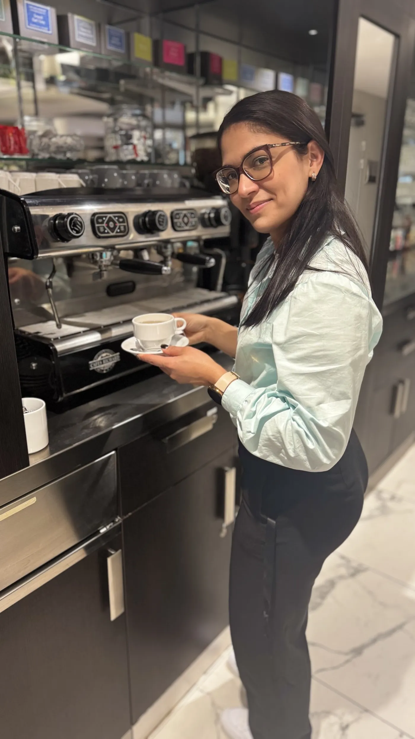 Une membre de l'équipe du restaurant tient une tasse devant la machine à café