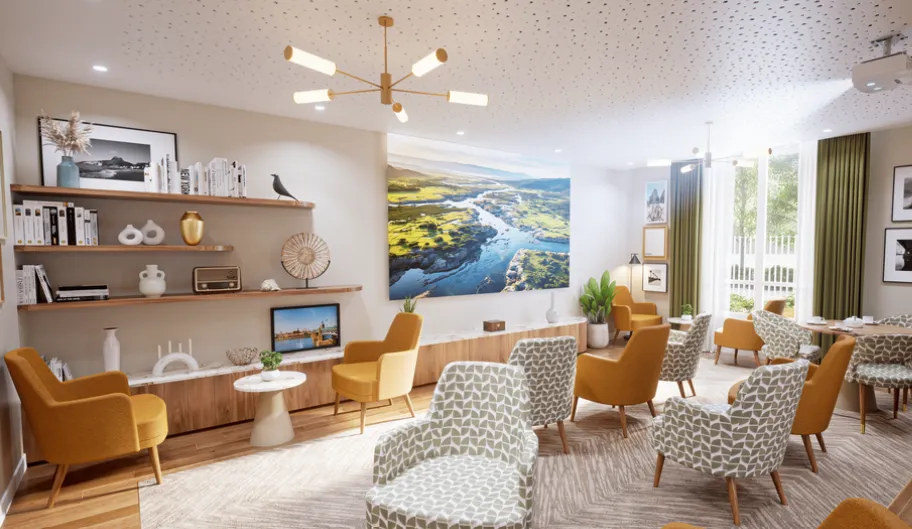 Library lounge of the OBEO Toulouse-Guillaumet residence: yellow and patterned armchairs, well-stocked shelves and a large photograph of the Garonne